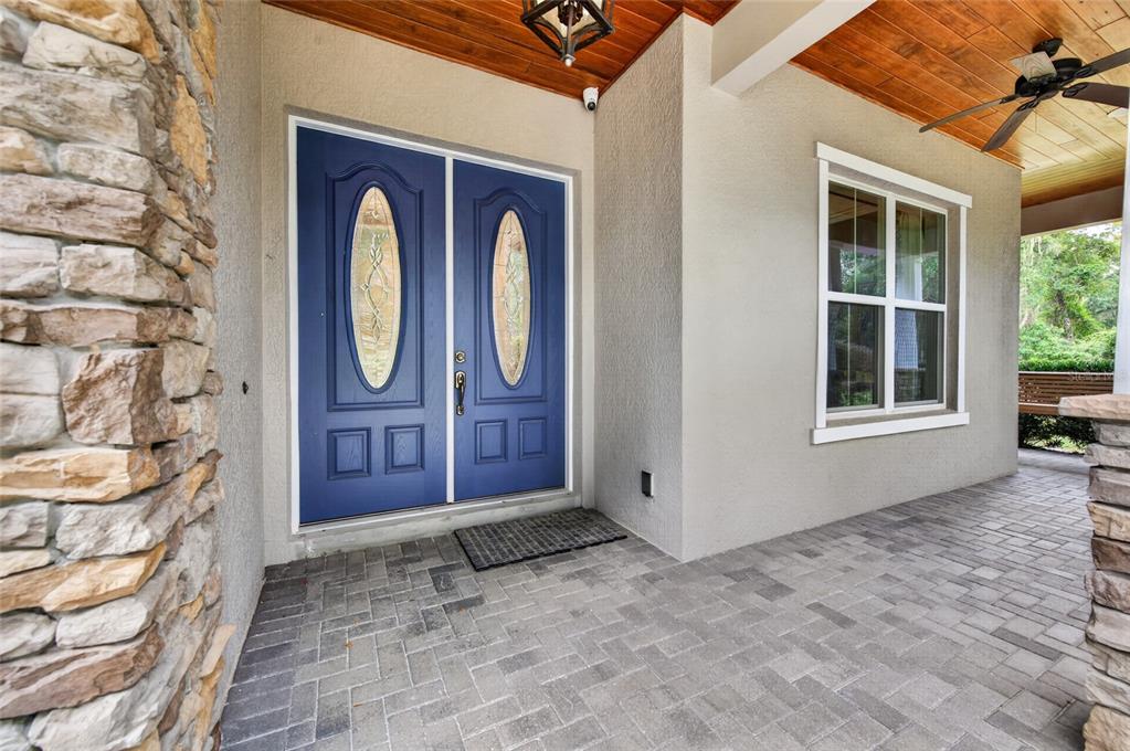 A covered porch features a blue double front door, stone siding, and a ceiling fan — 1515 RAMBLING OAKS LANE, DELAND, FL