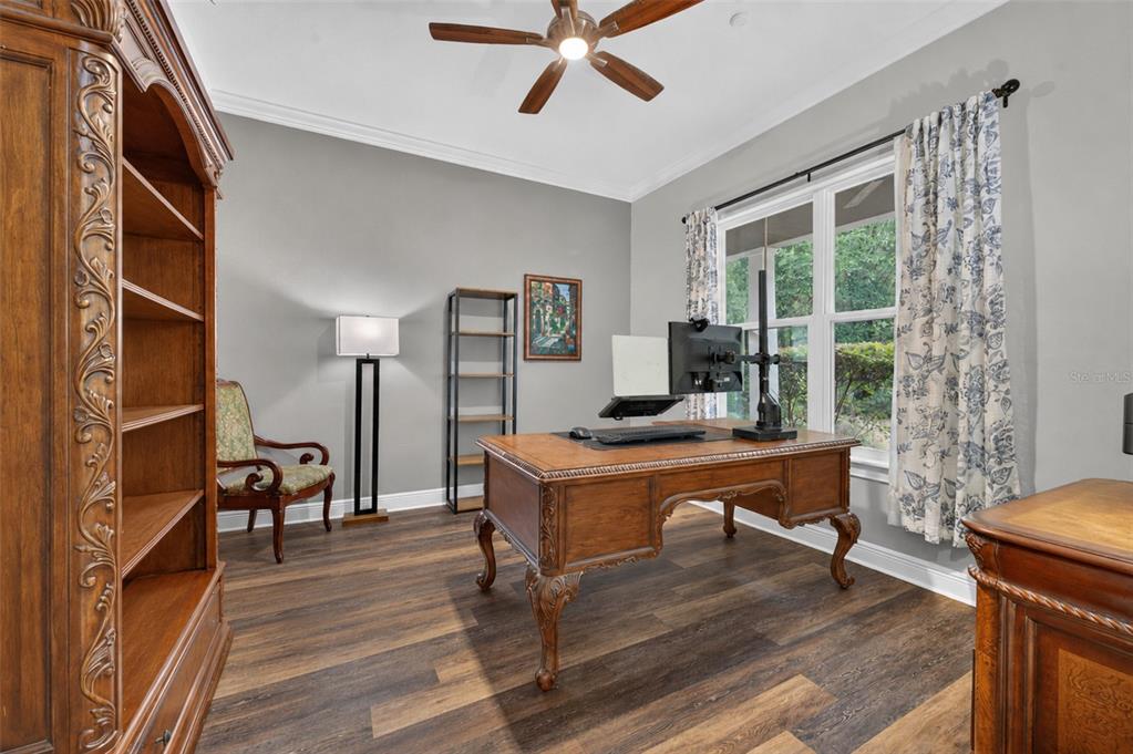 A home office features a wooden desk, a ceiling fan, and a large bookshelf — 1515 RAMBLING OAKS LANE, DELAND, FL