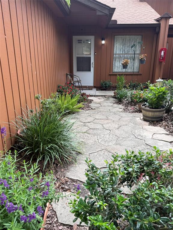 A stone walkway leads to a white front door beside a brown wood-sided house — 2701 NE 10TH STREET UNIT 401, OCALA, FL
