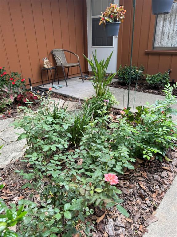 A small patio features a chair, potted plants, and a garden bed with roses — 2701 NE 10TH STREET UNIT 401, OCALA, FL