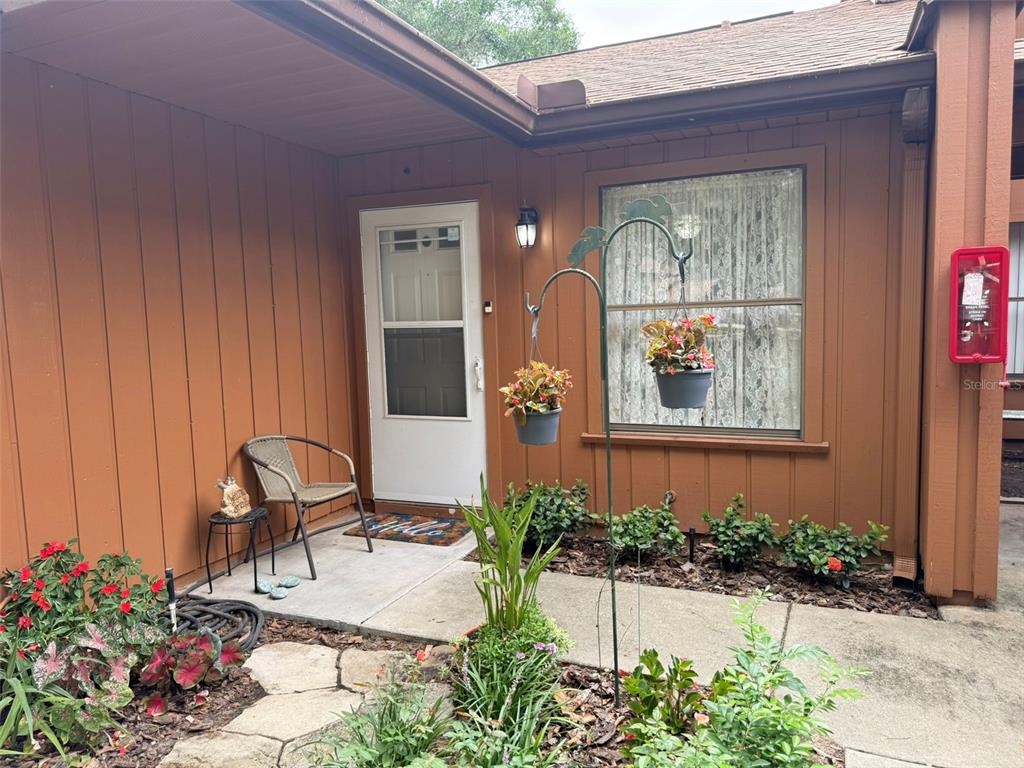 A brown exterior wall features a white front door, a window, and a hanging plant stand — 2701 NE 10TH STREET UNIT 401, OCALA, FL