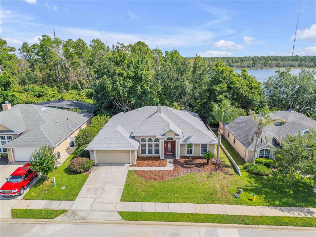 An aerial view of a single-story suburban house with a gray roof and lakefront backyard — 625 QUAIL LAKE DRIVE, DEBARY, FL