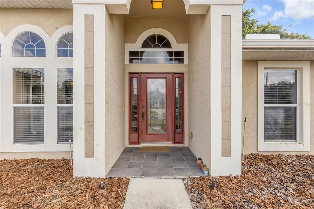 The front entrance features a red door with glass inserts, a transom window, and tiled flooring — 625 QUAIL LAKE DRIVE, DEBARY, FL