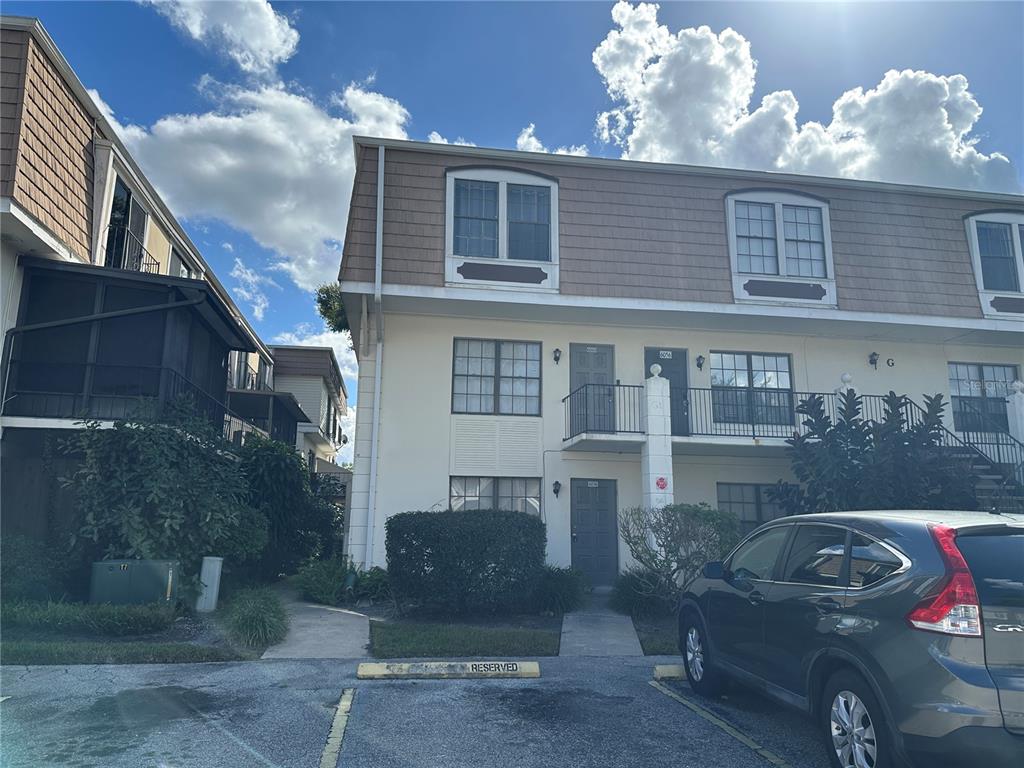 A multi-story apartment building with beige siding and a parking lot in the foreground — 6060 VILLAGE CIRCLE UNIT 6060, ORLANDO, FL