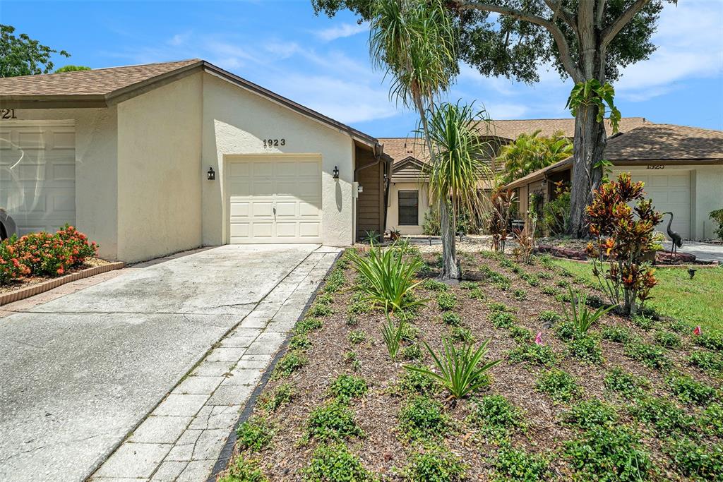 A beige house with a garage and a landscaped front yard under a blue sky — 1923 BAYSHORE COURT, SAFETY HARBOR, FL
