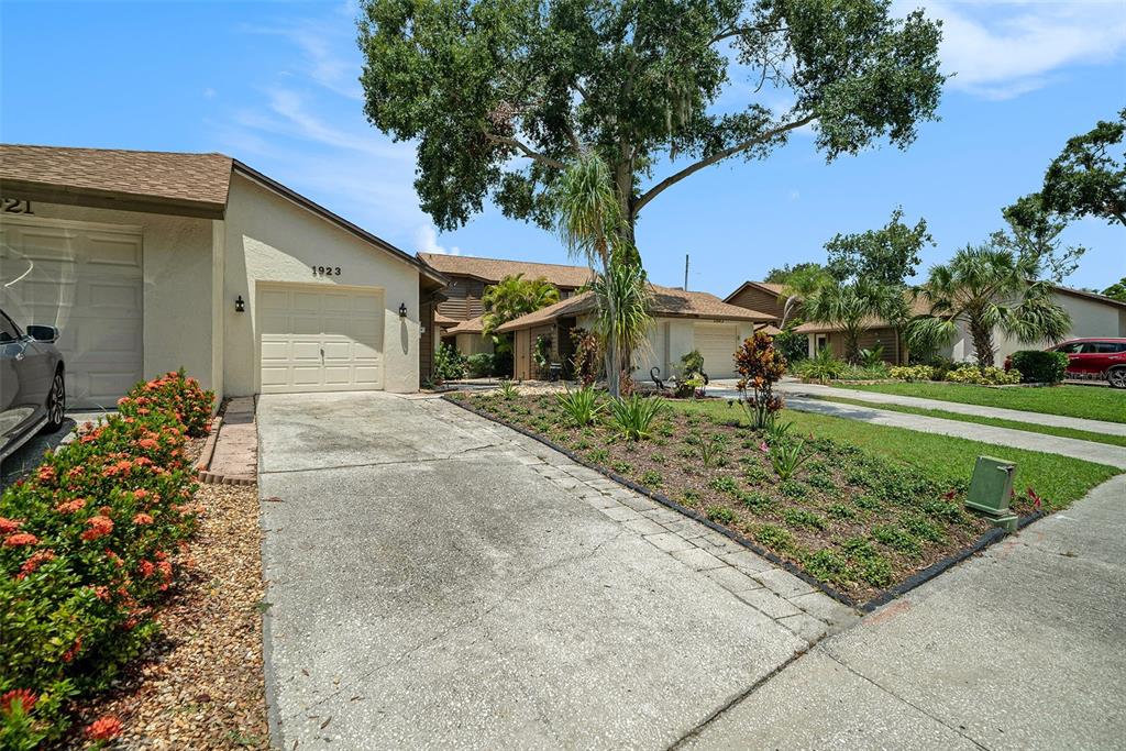 A concrete driveway leads to the garage of a single-story house with landscaping — 1923 BAYSHORE COURT, SAFETY HARBOR, FL