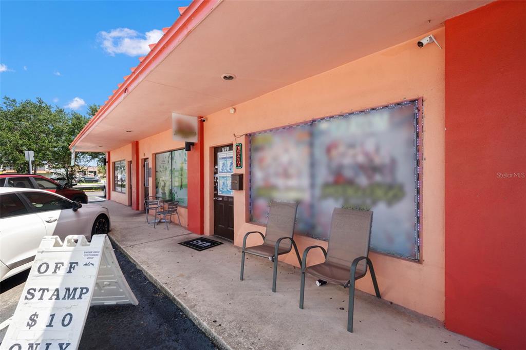 The exterior of a commercial storefront features a peach-colored wall, two chairs, and signage — 49TH STREET, PINELLAS PARK, FL