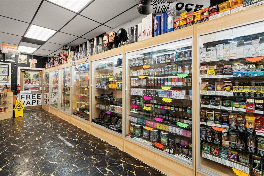 A retail smoke shop features glass display cases filled with products and a marble-patterned floor — 49TH STREET, PINELLAS PARK, FL