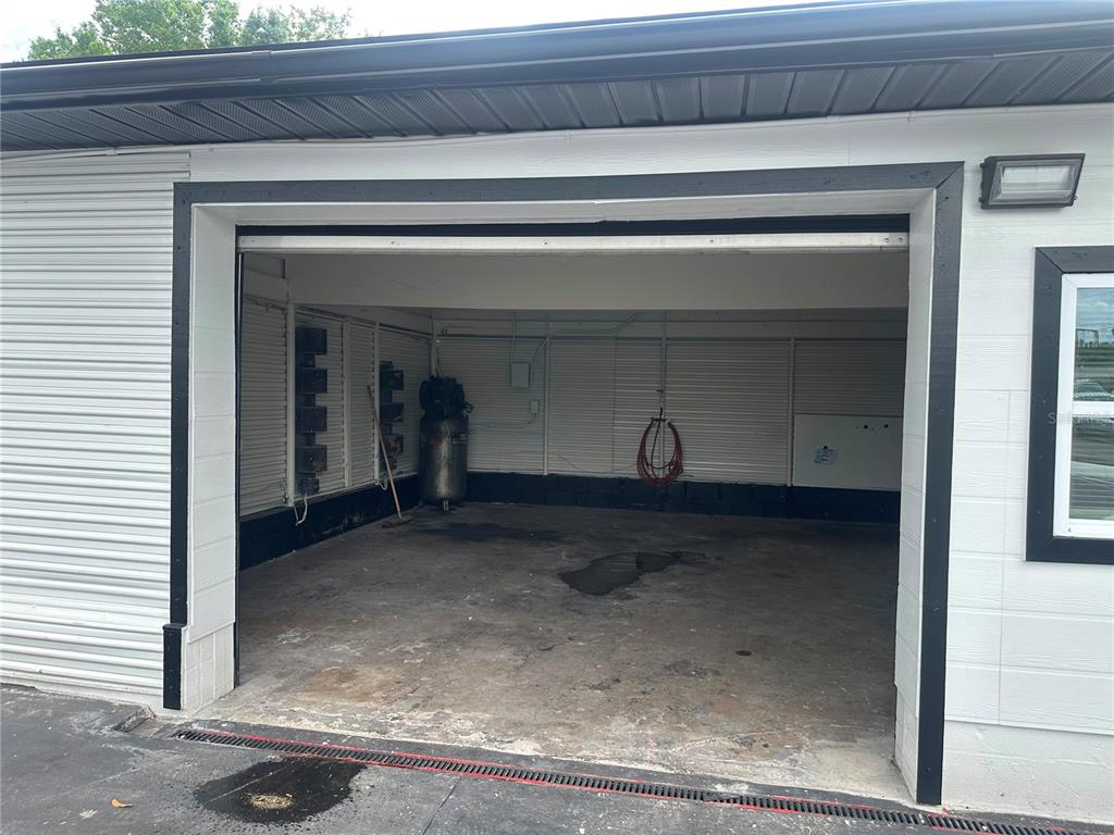 An open-bay garage features a concrete floor, white metal walls, and an air compressor — 607 FAIRVILLA ROAD, ORLANDO, FL