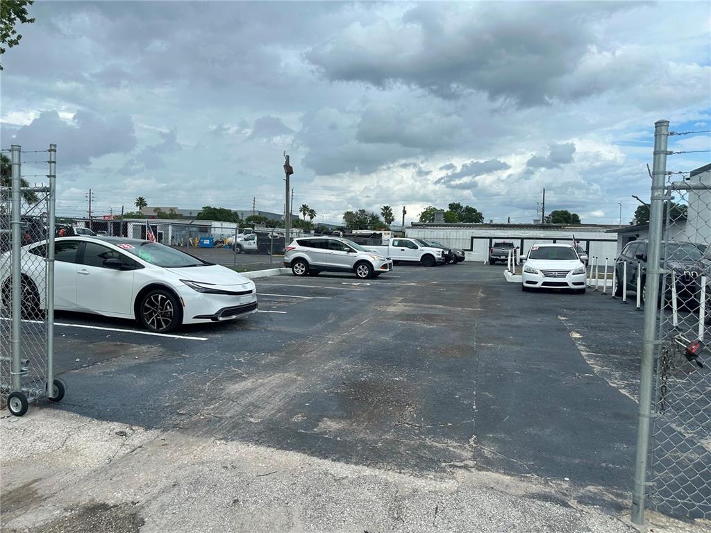 A paved parking lot with several parked cars is enclosed by a chain-link fence — 607 FAIRVILLA ROAD, ORLANDO, FL