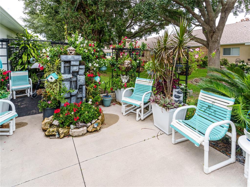 A patio features a stone water fountain, several potted plants, and light blue outdoor chairs — 9234 SANTA MONICA WAY, NEW PORT RICHEY, FL