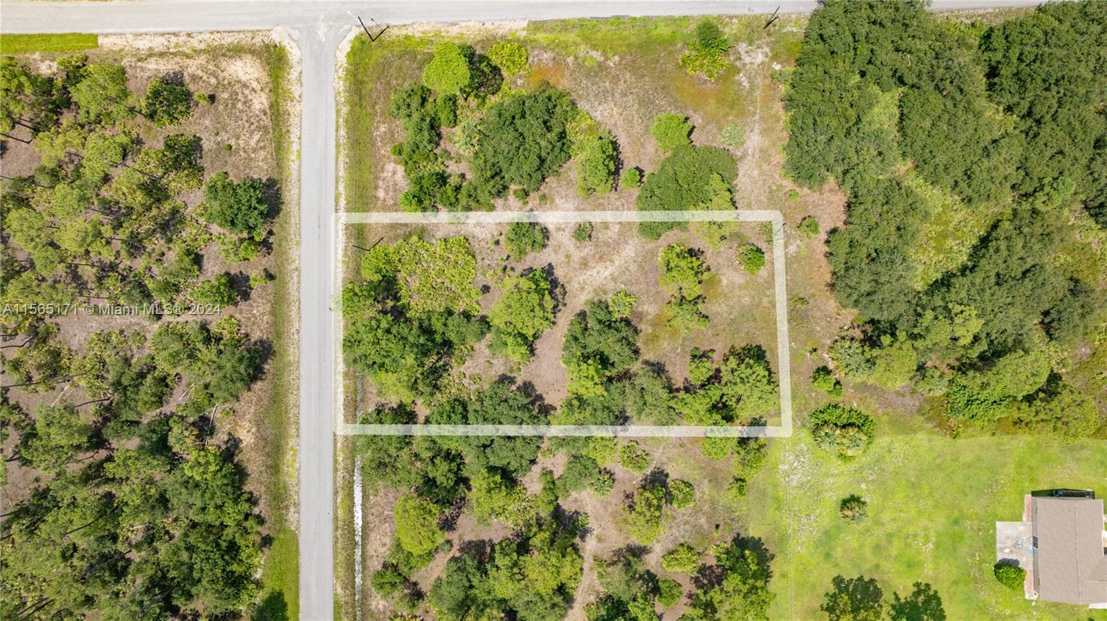 An aerial view shows a rectangular plot of undeveloped land bordered by a paved road — 1420 Clayton Ave, Lehigh Acres FL 33972, LEHIGH ACRES, FL