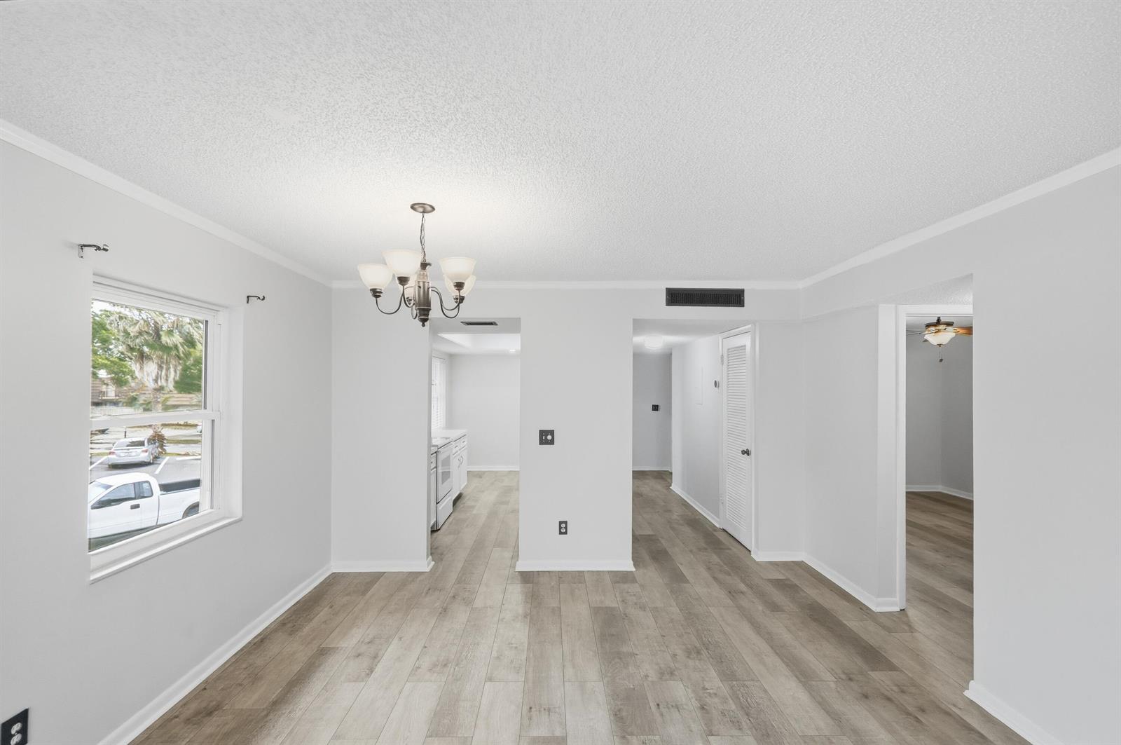 A dining area with a chandelier, light wood-look flooring, and doorways leading to other rooms — 1166 6th Avenue # B8, Vero Beach FL 32960, VERO BEACH, FL