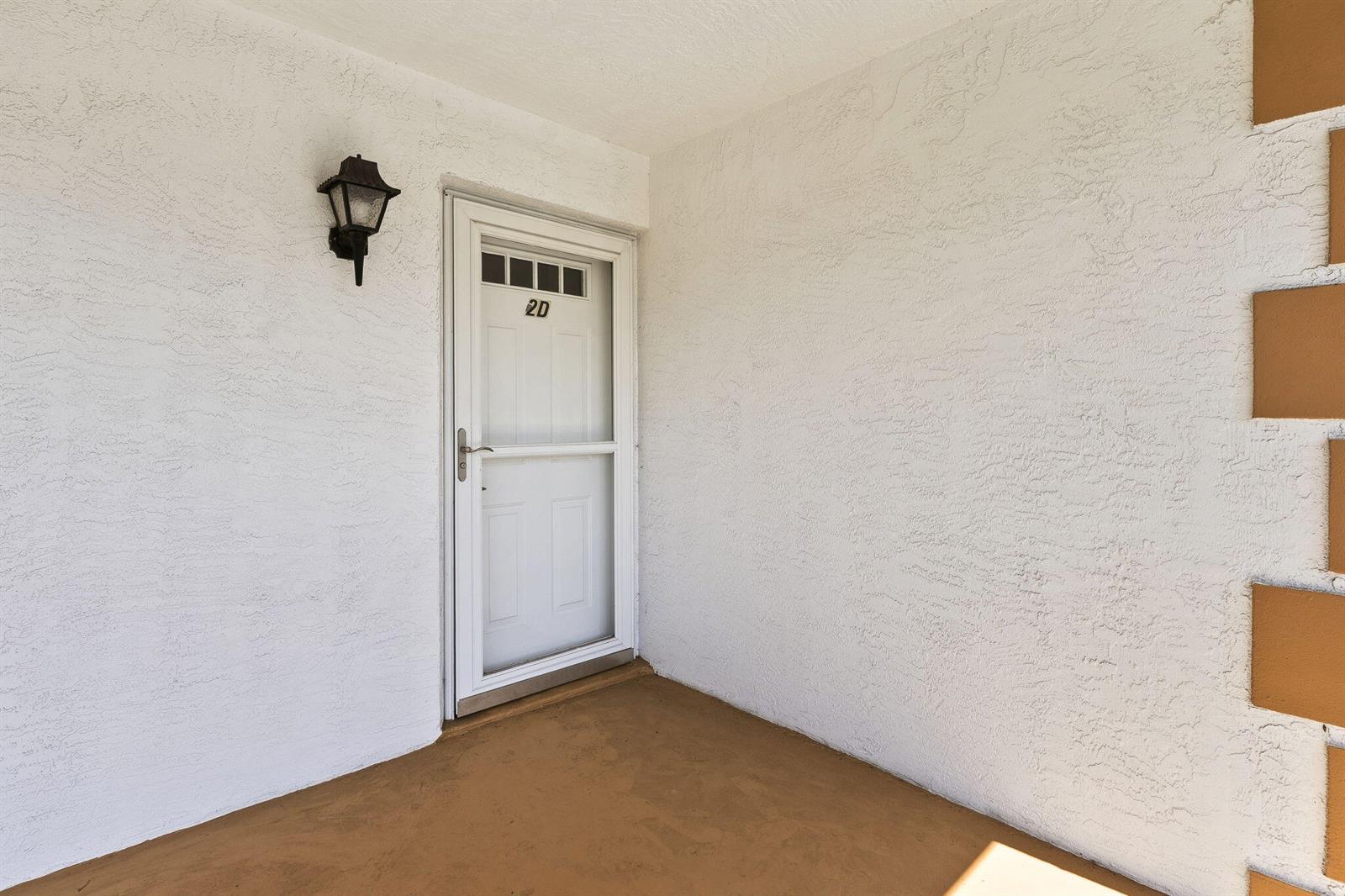 A white door marked 2D sits on a brown patio with textured white walls — 533 S Lakes End Drive # D2, Fort Pierce FL 34982, FORT PIERCE, FL