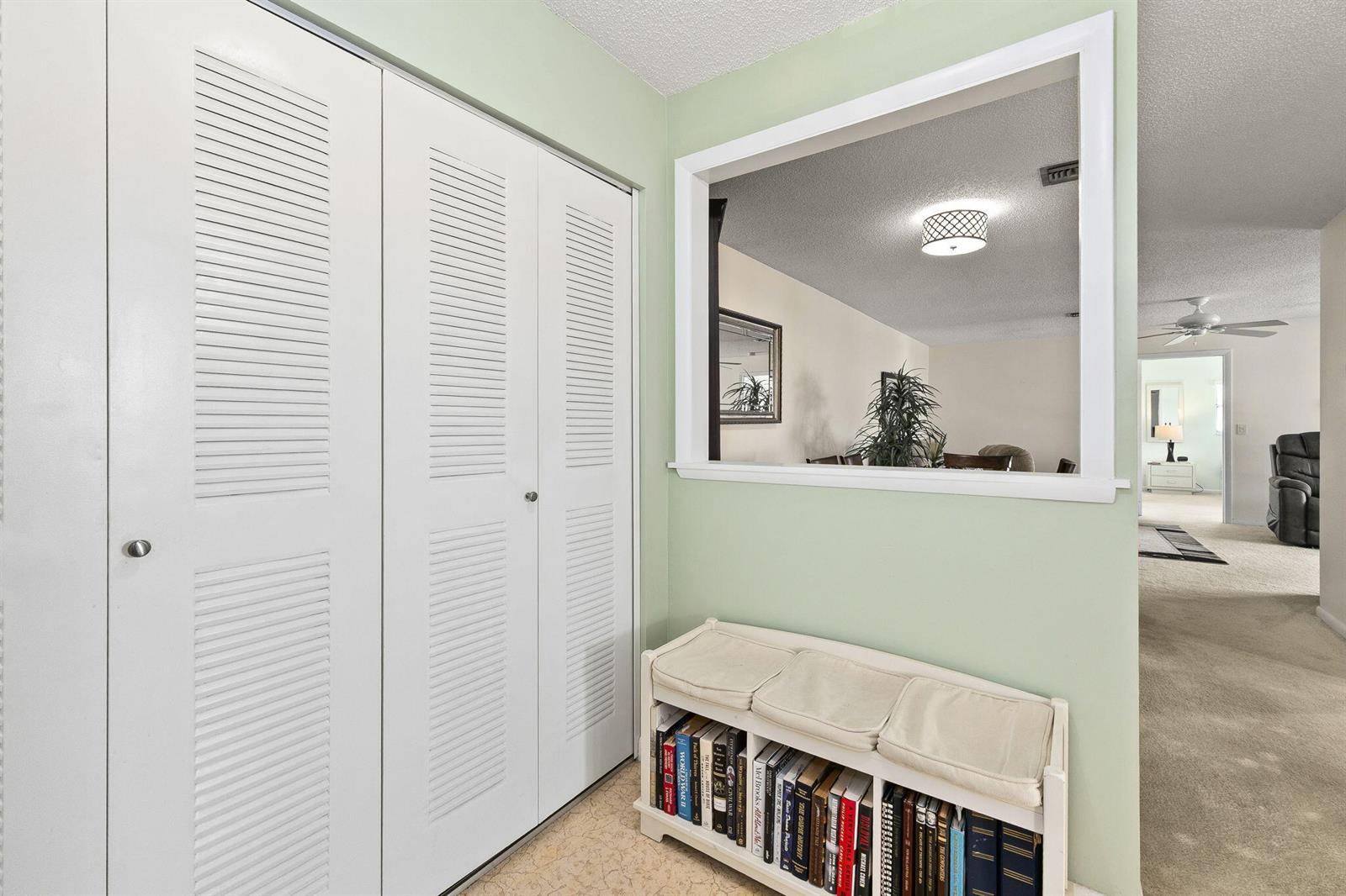 A hallway features white louvered closet doors, a built-in window cutout, and a book-filled bench — 533 S Lakes End Drive # D2, Fort Pierce FL 34982, FORT PIERCE, FL