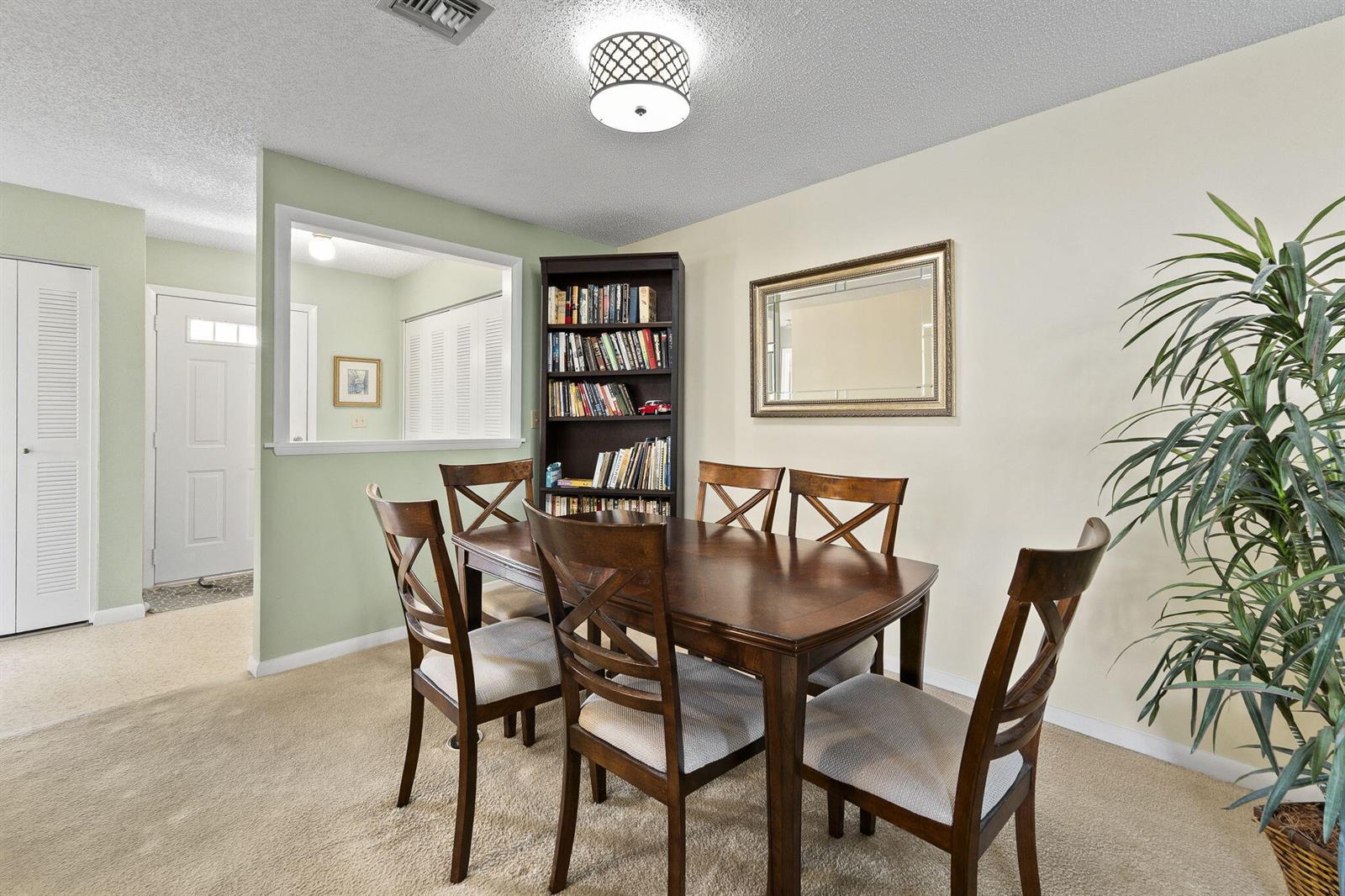 A dining room with a wooden table, four chairs, a bookshelf, and a wall mirror — 533 S Lakes End Drive # D2, Fort Pierce FL 34982, FORT PIERCE, FL
