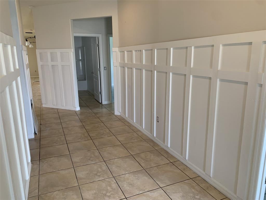 A hallway with tan tile flooring and white board-and-batten wainscoting on the walls — 3966 BAJA DRIVE, ST CLOUD, FL