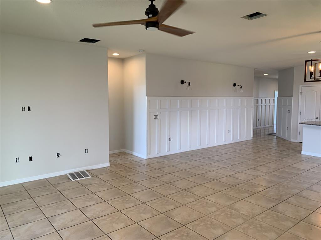 An open living area features tile flooring, a ceiling fan, and white board-and-batten wall paneling — 3966 BAJA DRIVE, ST CLOUD, FL