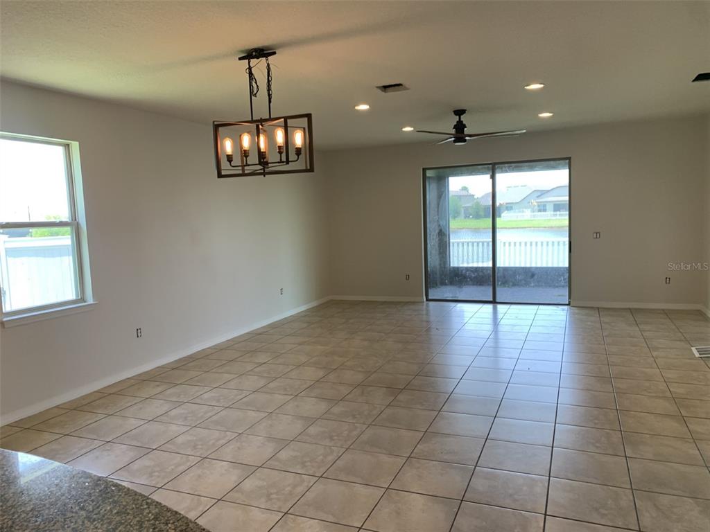 A spacious living area features tile flooring, a rectangular chandelier, and sliding glass patio doors — 3966 BAJA DRIVE, ST CLOUD, FL