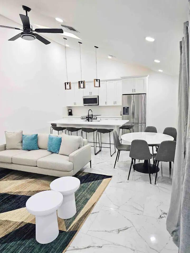An open-concept kitchen and living area with white cabinetry, a kitchen island, and marble flooring — 1255 PERIWINKLE Place, Wellington FL 33414, WELLINGTON, FL