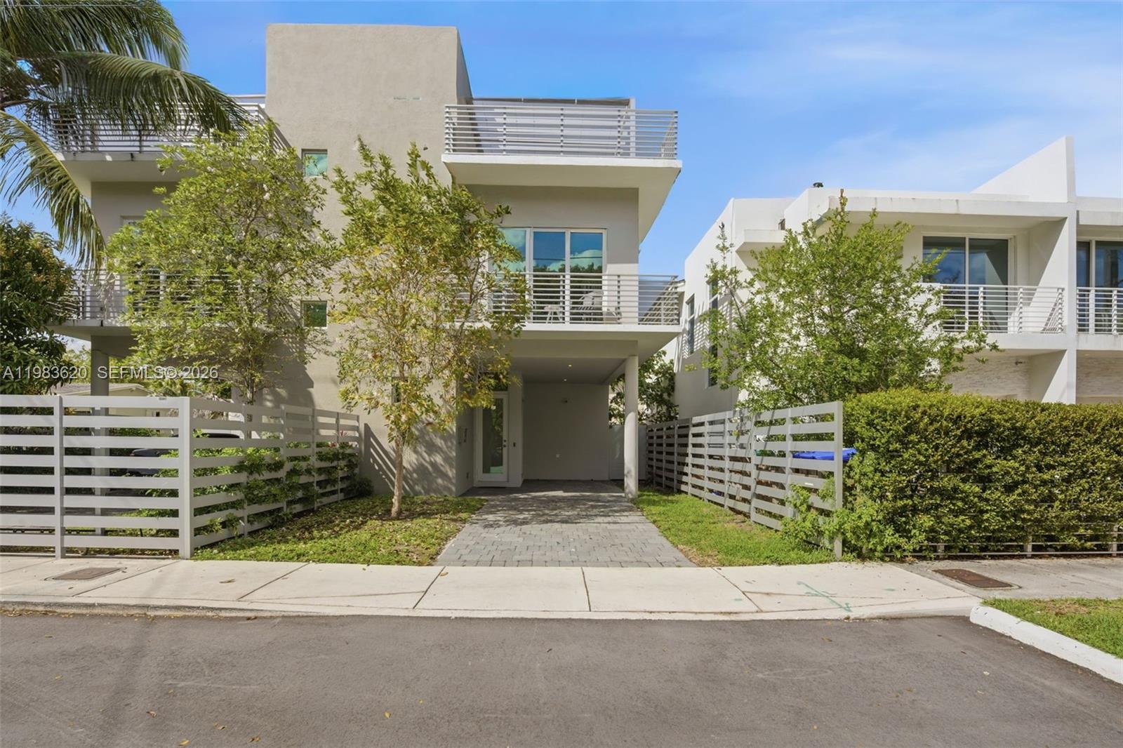 A modern three-story house features a paved driveway, a covered entrance, and horizontal slat fencing — 3525 Day Ave, Miami FL 33133, MIAMI, FL