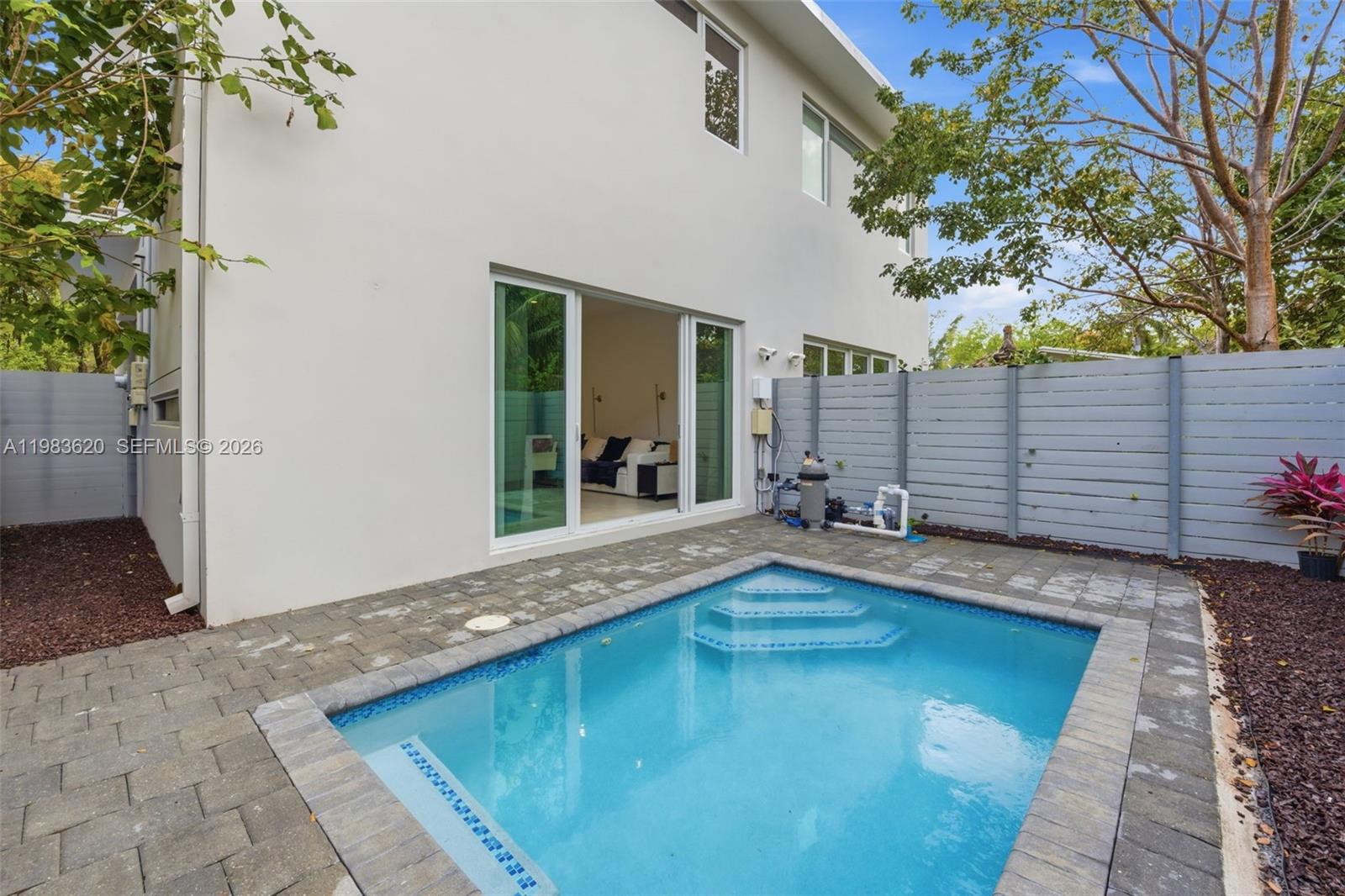 A small backyard pool sits on a paved patio next to a modern white house — 3525 Day Ave, Miami FL 33133, MIAMI, FL