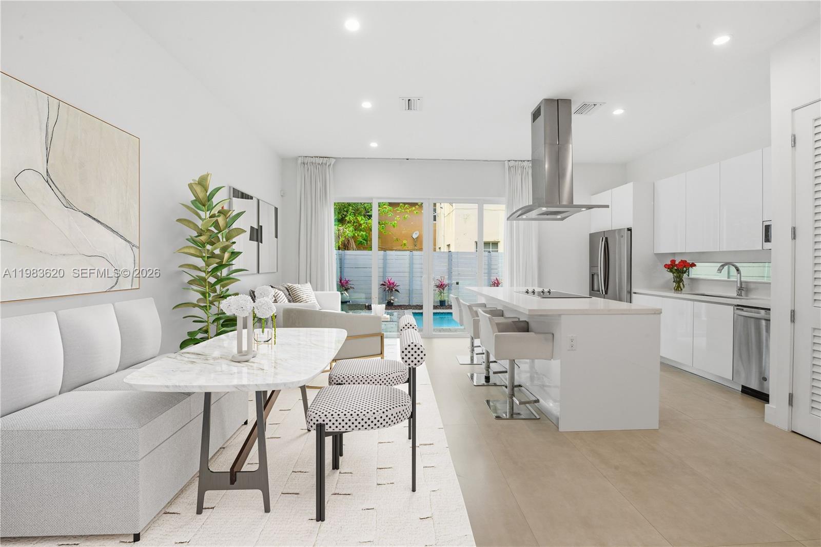 A modern open-concept kitchen and dining area features a marble table, island, and pool view — 3525 Day Ave, Miami FL 33133, MIAMI, FL