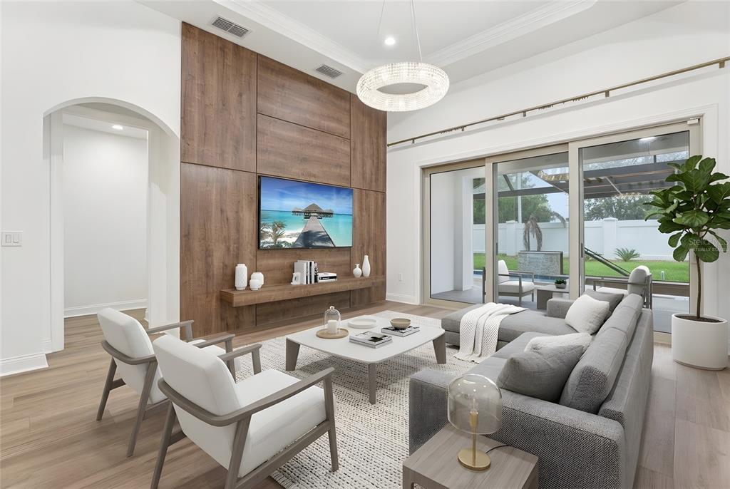 A modern living room features a wood-paneled accent wall, a television, and sliding glass doors — 10409 ANGEL OAK COURT, ORLANDO, FL
