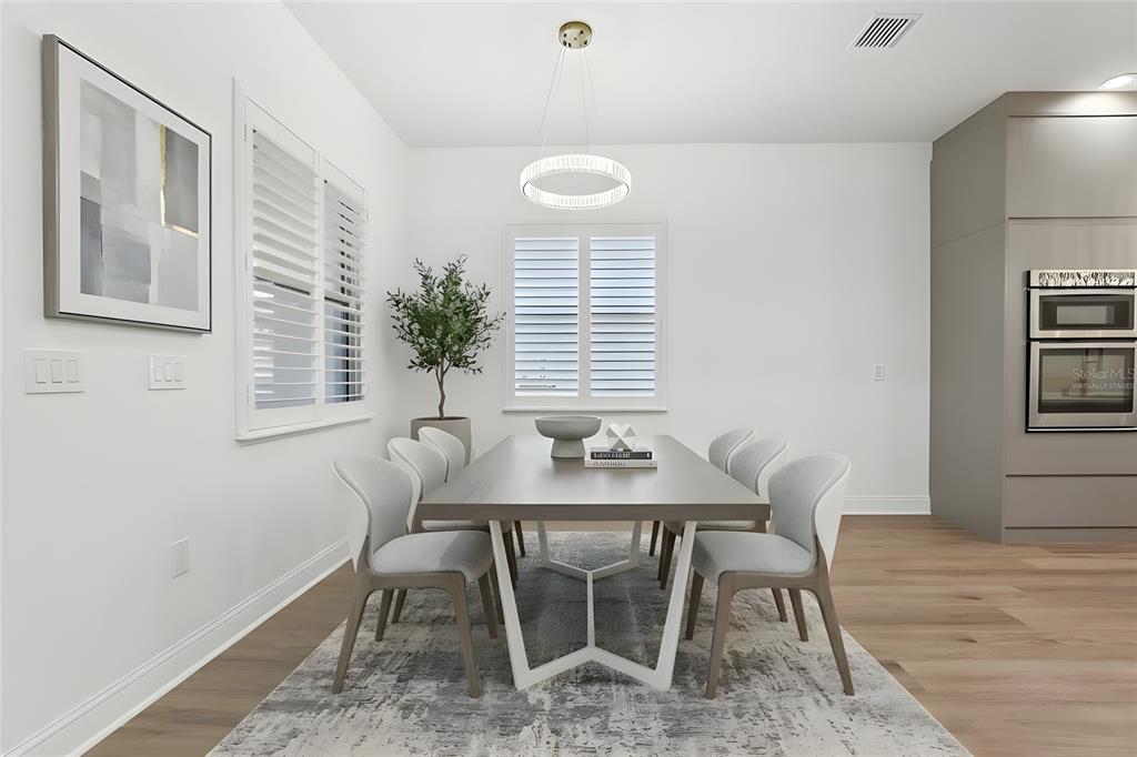 A dining room features a modern table with six chairs, a chandelier, and wood flooring — 10409 ANGEL OAK COURT, ORLANDO, FL