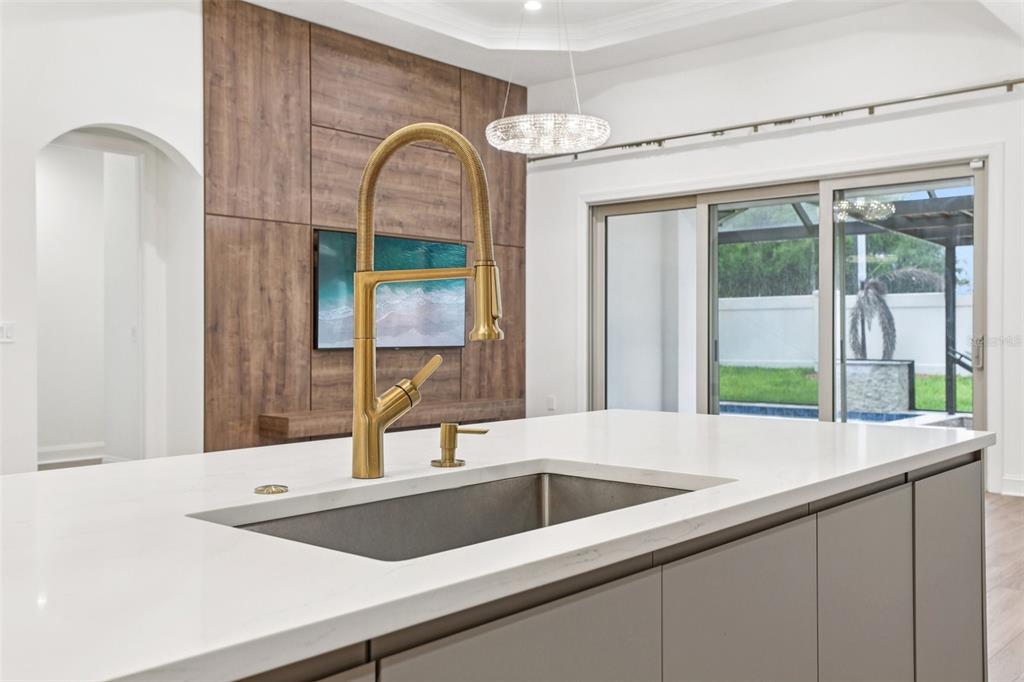 A kitchen island with a gold faucet and white countertop sits before a wood-paneled wall — 10409 ANGEL OAK COURT, ORLANDO, FL