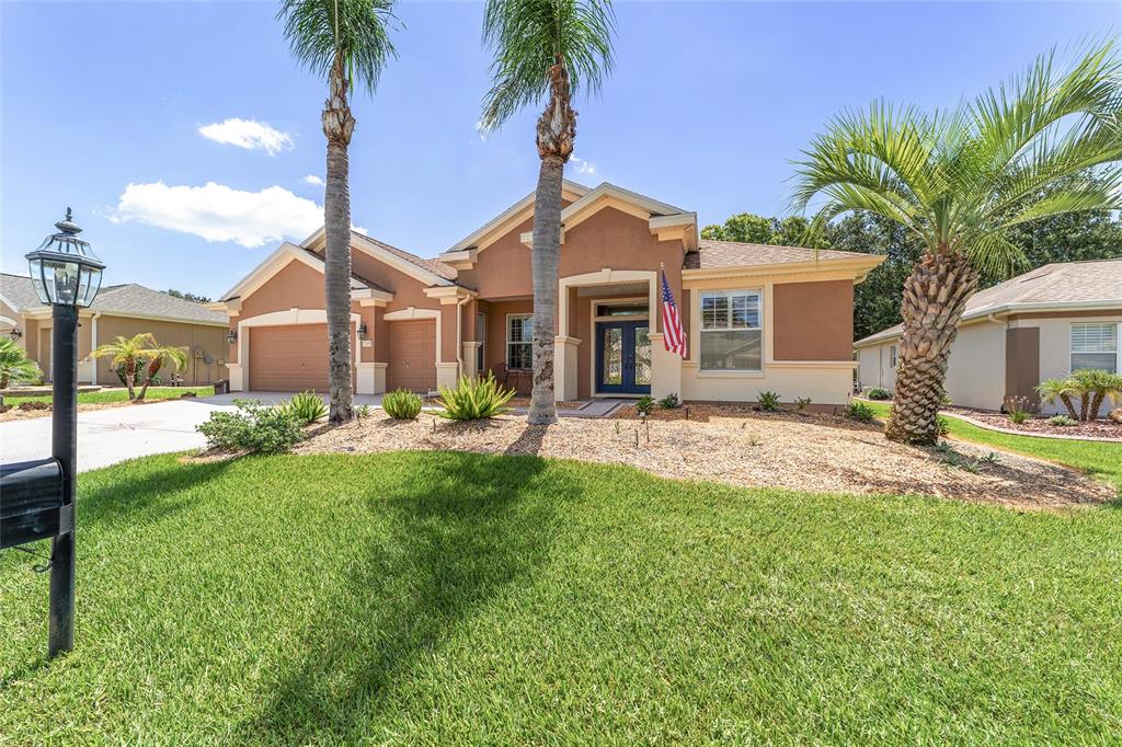 A single-story house with a tan stucco exterior, two palm trees, and a front lawn — 12859 SE 91ST TERRACE ROAD, SUMMERFIELD, FL