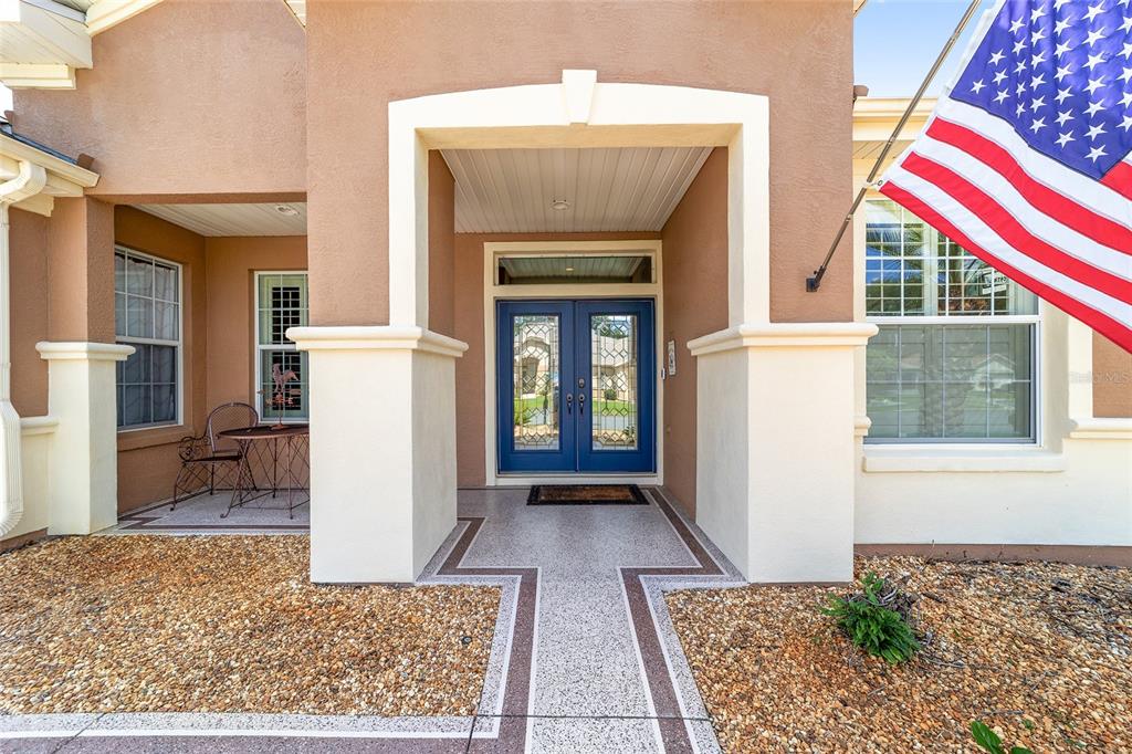 A front entryway features a blue double door, a concrete walkway, and an American flag — 12859 SE 91ST TERRACE ROAD, SUMMERFIELD, FL