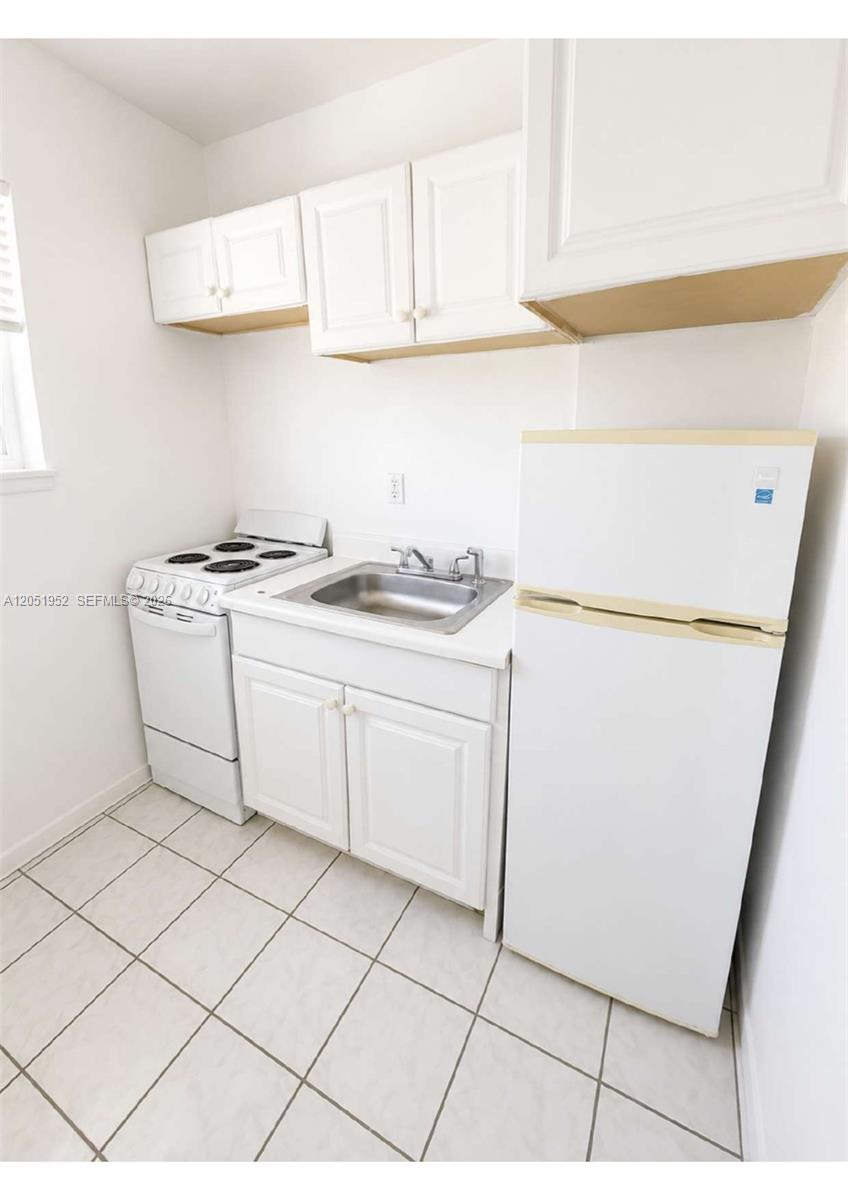 A small kitchen features white cabinets, a stove, a sink, and a refrigerator — 5305 Biscayne Blvd # 203, Miami FL 33137, MIAMI, FL