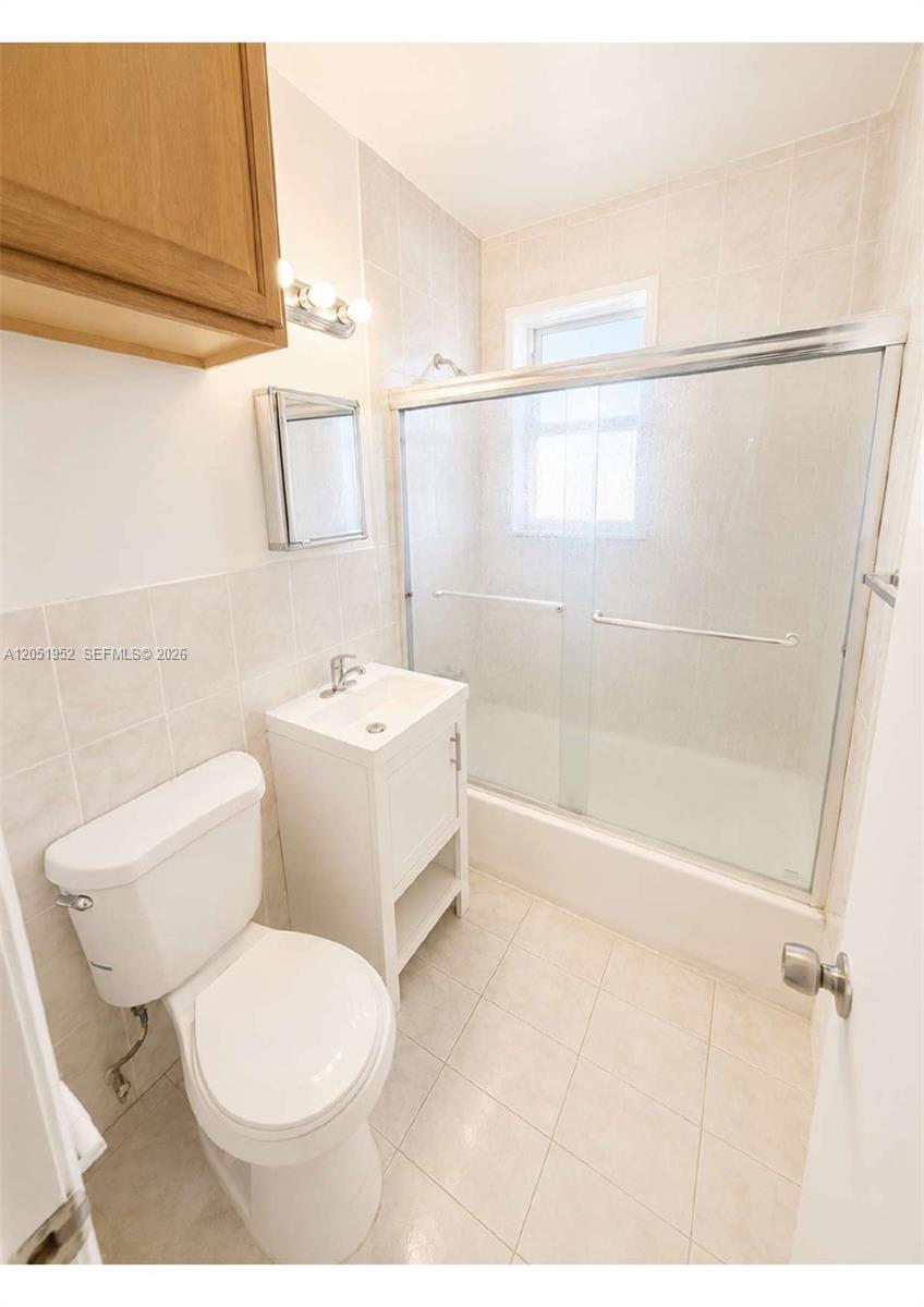 A bathroom features a white toilet, a small pedestal vanity, and a glass-enclosed shower — 5305 Biscayne Blvd # 203, Miami FL 33137, MIAMI, FL
