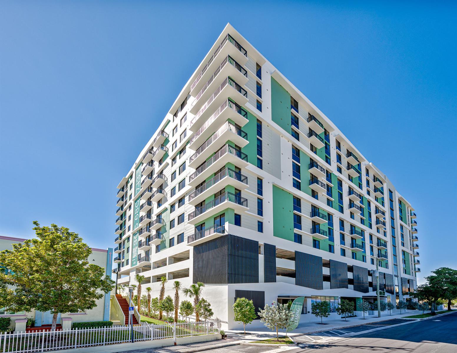 A modern multi-story apartment building with green accents, balconies, and a ground-level parking garage — 450 SW 5th Street # 401, Miami FL 33130, MIAMI, FL