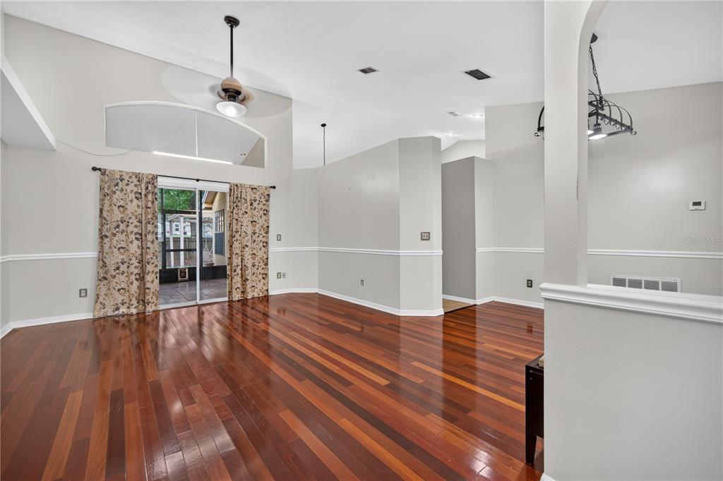 A living room with hardwood floors, vaulted ceilings, and sliding glass doors leading to a patio — 2600 CLEMENTON PARK COURT, ORLANDO, FL