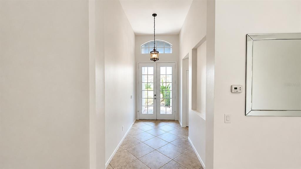A bright entryway features a tiled floor, a hanging lantern light, and double glass doors — 6836 BAY HILL DRIVE, LAKEWOOD RANCH, FL