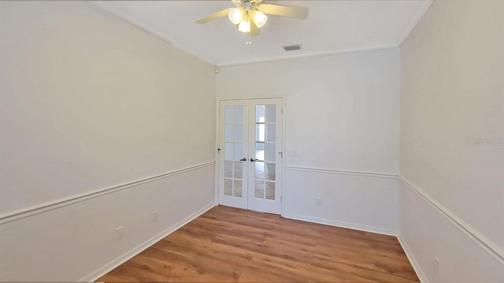 A room with white walls, chair rail molding, wood-look flooring, and French doors — 6836 BAY HILL DRIVE, LAKEWOOD RANCH, FL