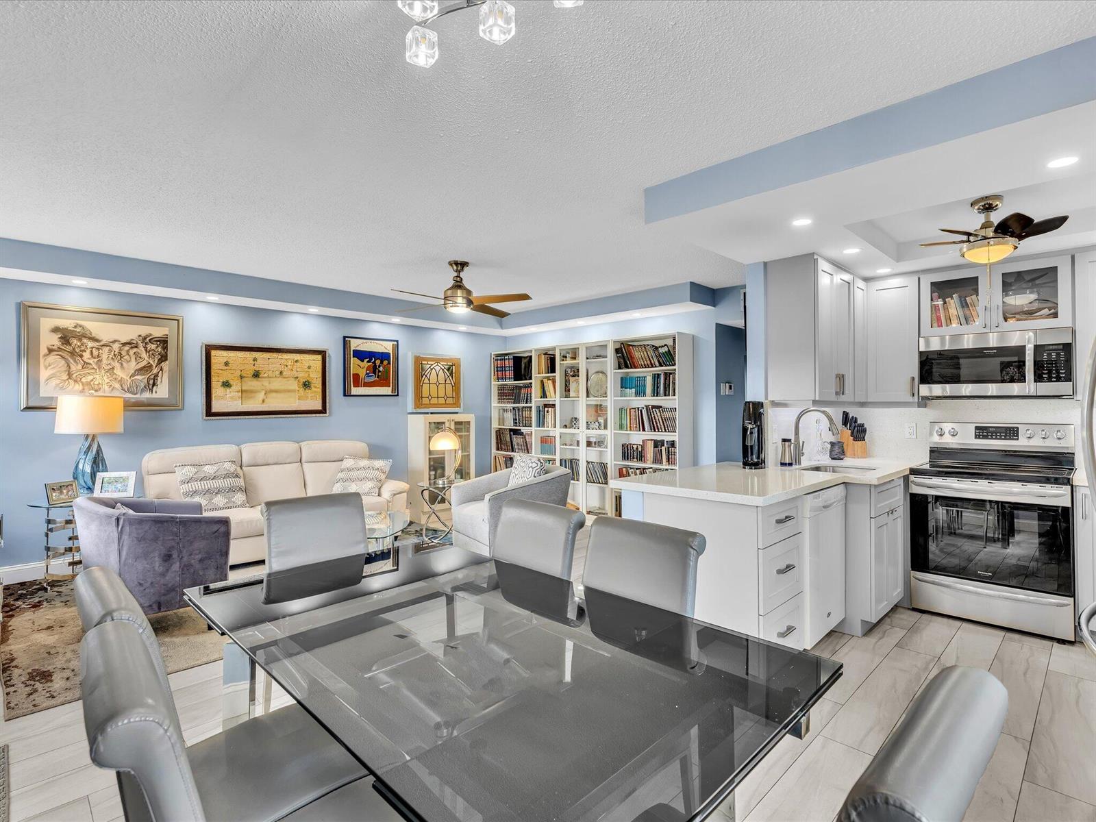 A dining area, living room, and kitchen with light blue walls and white cabinetry — 4038 Swansea B, Deerfield Beach FL 33442, DEERFIELD BEACH, FL