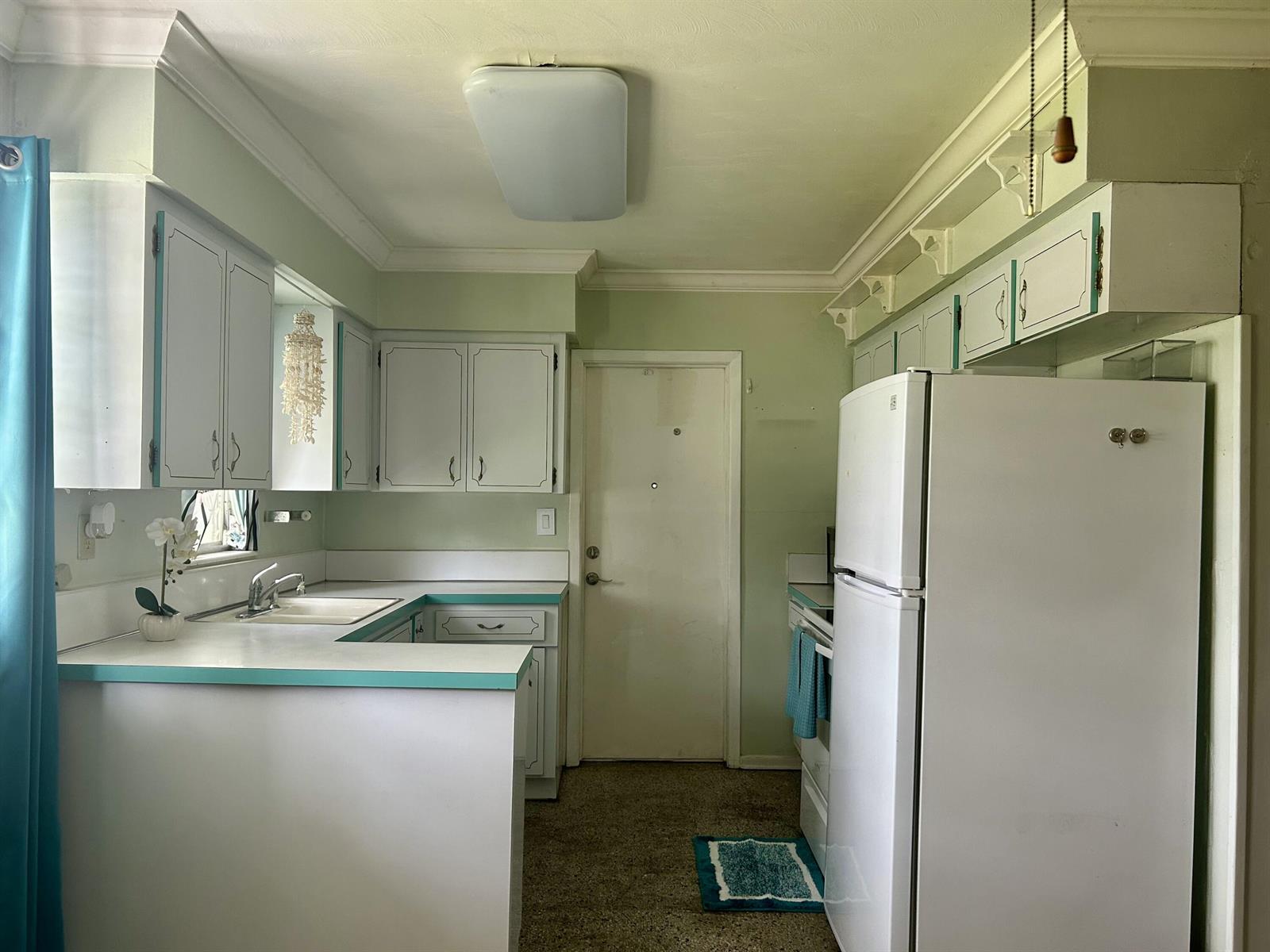 A kitchen features white cabinets with teal trim, white countertops, and a white refrigerator — 3632 NW 25th Avenue, Okeechobee FL 34972, OKEECHOBEE, FL