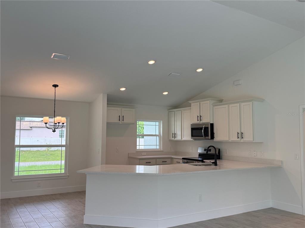 A kitchen with white cabinets, light countertops, and a dining area with a chandelier — 5600 CASANOVA AVENUE, NORTH PORT, FL