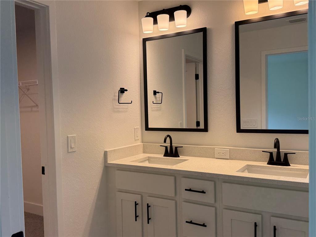 A bathroom features a double vanity with white cabinets, black fixtures, and two framed mirrors — 5600 CASANOVA AVENUE, NORTH PORT, FL