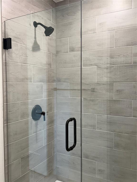 A glass-enclosed shower features gray wood-look tile walls and matte black fixtures — 5600 CASANOVA AVENUE, NORTH PORT, FL
