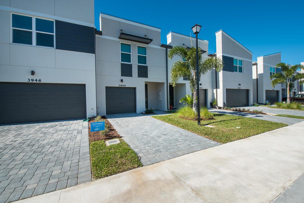 A row of modern townhomes with gray garage doors, paved driveways, and small palm trees — 3944 SE Caladium Court, Stuart FL 34997, STUART, FL
