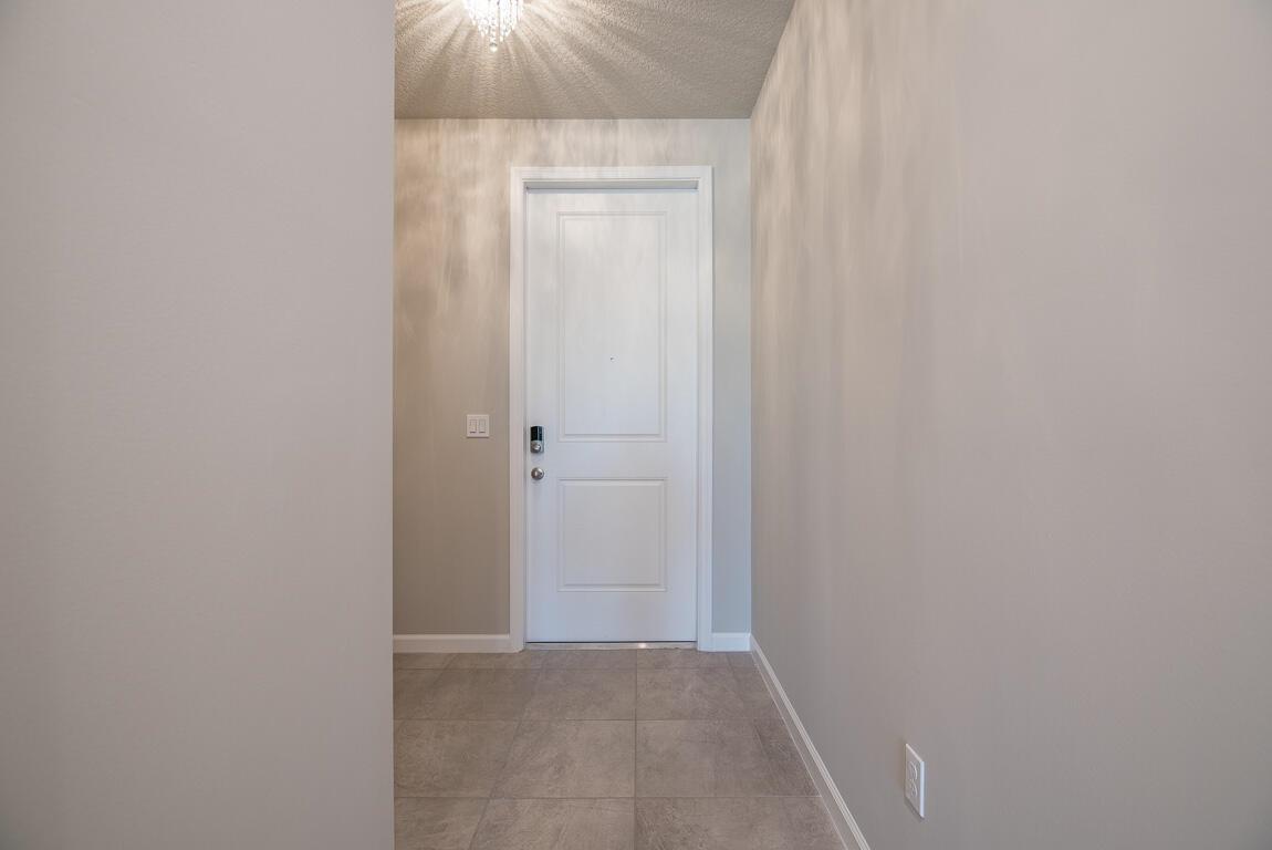 A view of a small entryway with a white door, light walls, and tiled flooring — 3944 SE Caladium Court, Stuart FL 34997, STUART, FL