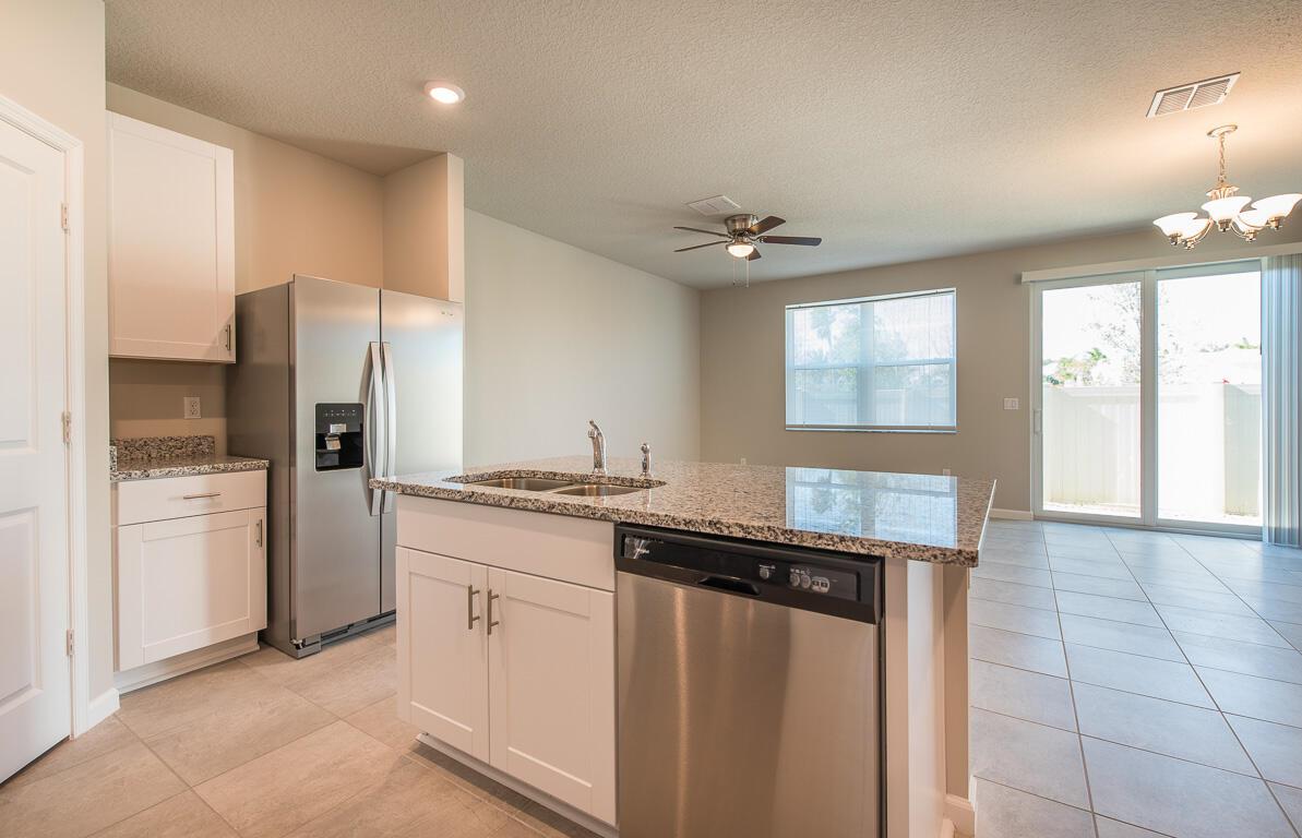 A kitchen with white cabinets, granite countertops, stainless steel appliances, and tile flooring — 3944 SE Caladium Court, Stuart FL 34997, STUART, FL