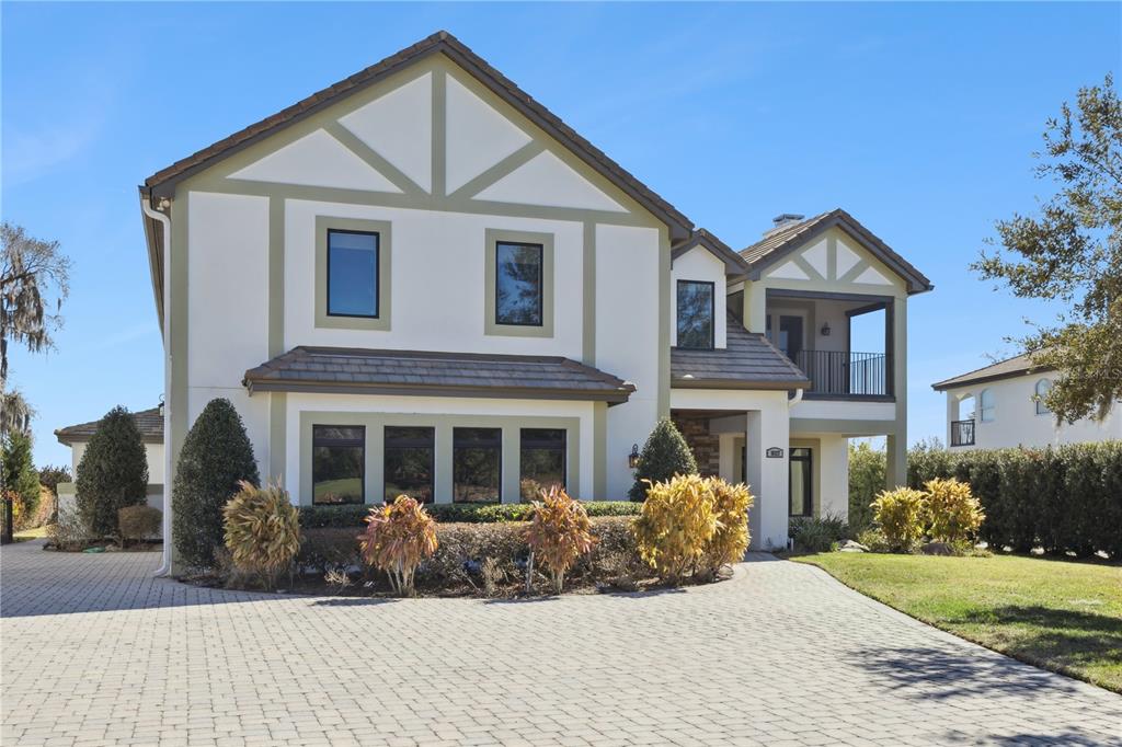 A two-story house with a paved driveway, stucco exterior, and a balcony on the right — 10327 HART BRANCH CIRCLE, ORLANDO, FL