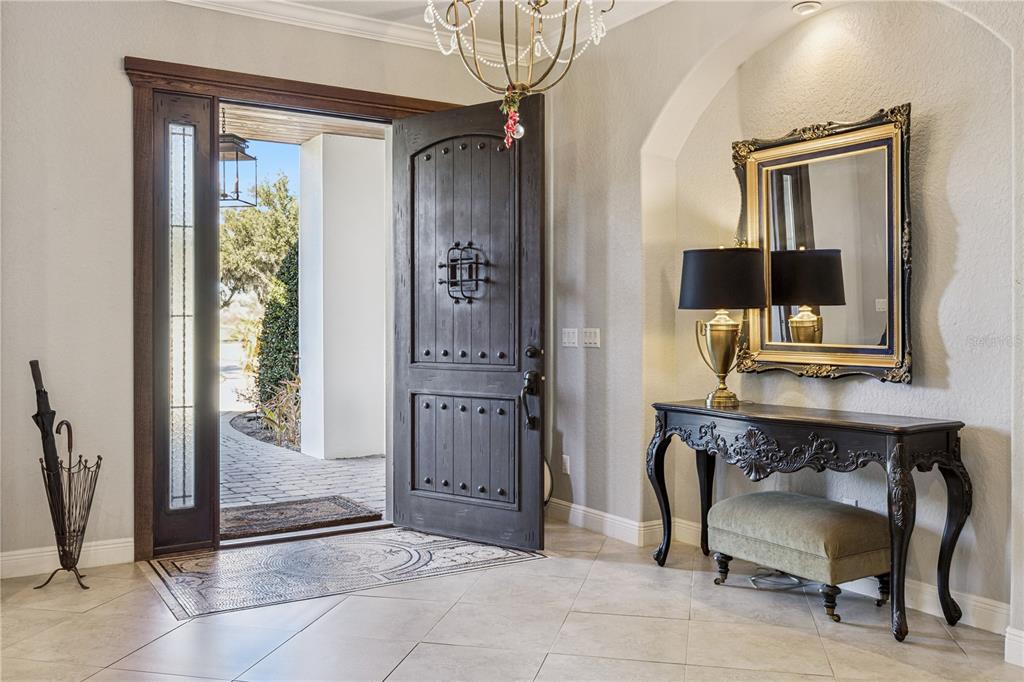 An entryway features a dark wood door, tiled floors, a console table, and a mirror — 10327 HART BRANCH CIRCLE, ORLANDO, FL