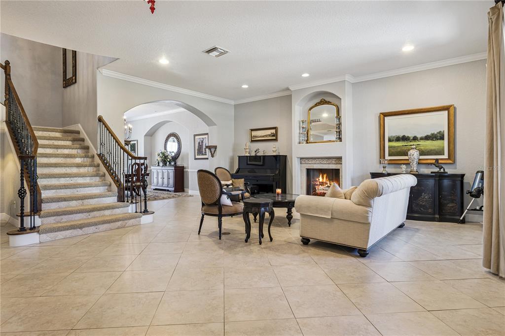A spacious living room features a staircase, a fireplace, tile flooring, and traditional furniture — 10327 HART BRANCH CIRCLE, ORLANDO, FL