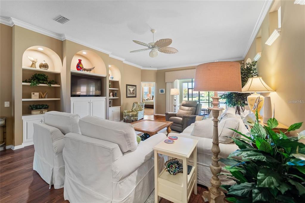 A living room features white slipcovered furniture, built-in shelving, and a ceiling fan — 5175 CANTABRIA CREST, SARASOTA, FL